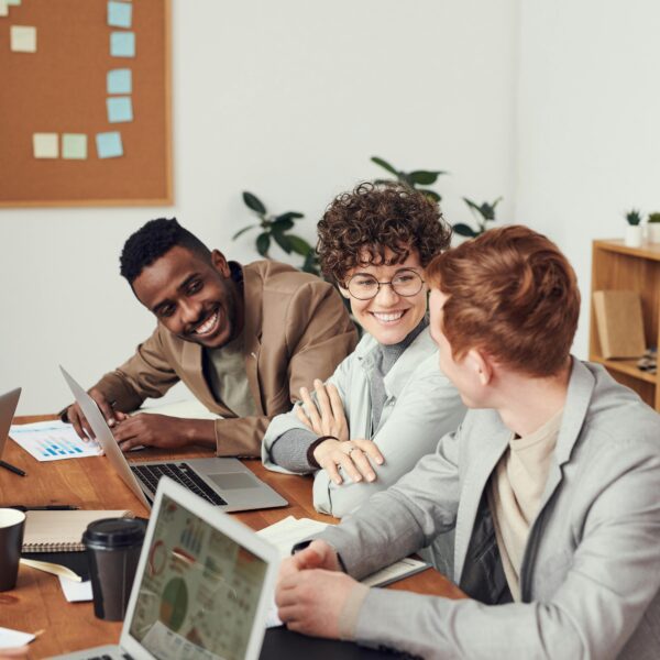 A group of people sitting around a table with laptops.